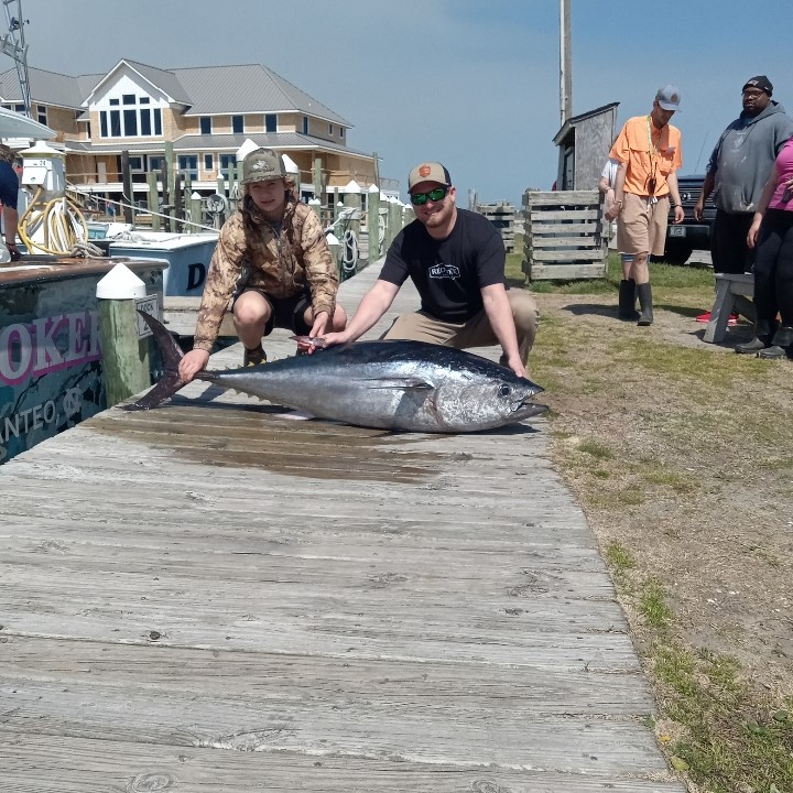 Two people pose with a giant tuna after a fishing charter trip in Outer Banks, NC.