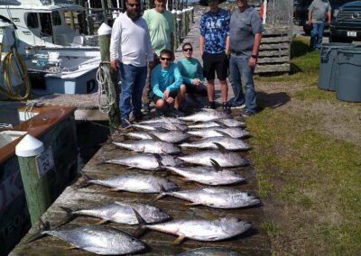 A group of people pose with tuna after a fishing charter trip in Outer Banks, NC.