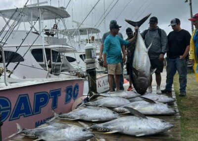 A group of people pose in front of a 9 large tuna they caught on a fishing charter in Outer Banks, NC.