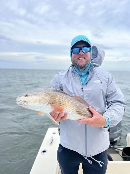 A person holds up a light gold fish they caught while on a fishing charter in Outer Banks, NC.