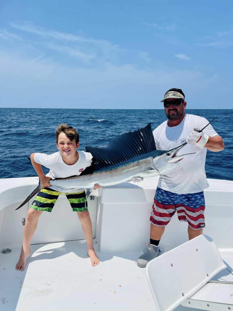 A man and a child hold up a large sailfish they caught while on a fishing charter in Outer Banks, NC.